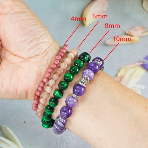 En arm med fyra armband i olika storlekar och färger.