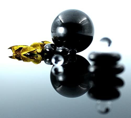 Svarta sfärer och gula blad på en reflekterande yta