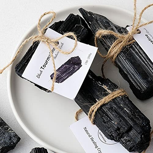 Svarta turmalinkristaller med etiketter och snören på en tallrik.