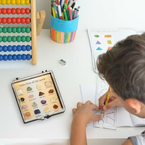 Barn ritar vid bordet med surfplatta och abacus.