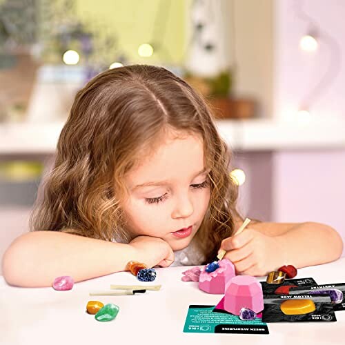 Barn som målar rosa stenar inomhus med pensel.