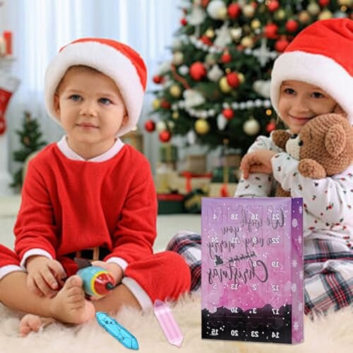 Två barn i tomteluvor sitter vid julgran med presenter.