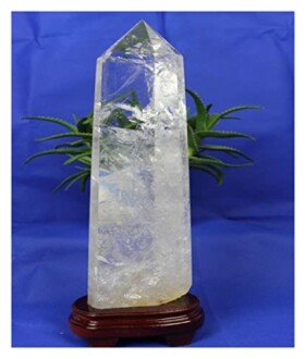 Klar kvarts kristallpunkt med växt i bakgrunden