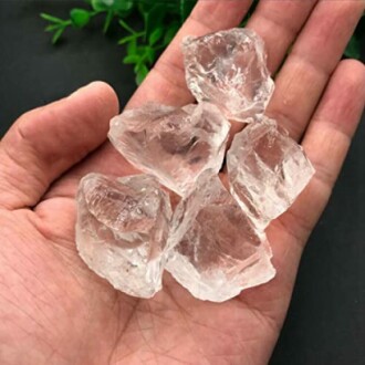 Fem klara kvartskristaller i en hand.
