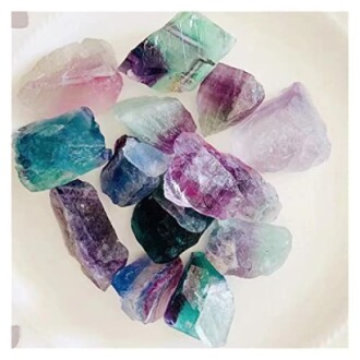 Flera färgglada råa fluoritstenar på en vit bakgrund.