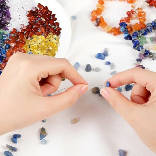 Händer som skapar smycken med pärlor och ädelstenar.