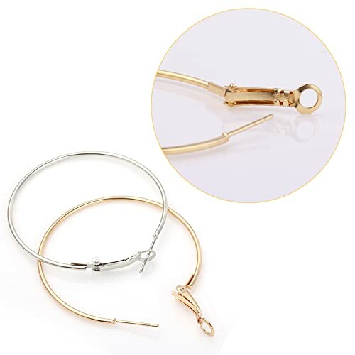 Två örhängen, ett i guld och ett i silver, med låsdetalj.