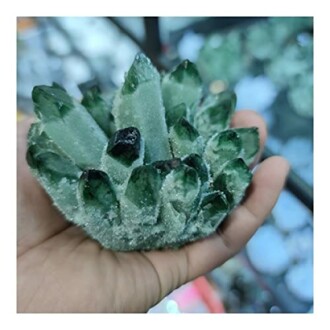 Grön kristallkluster i handflatan