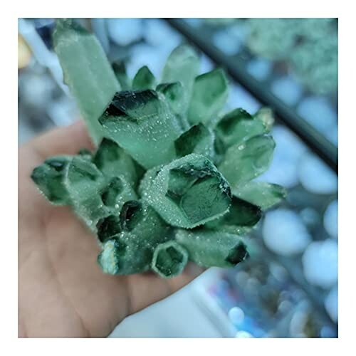 Hand håller en grön kristallkluster.