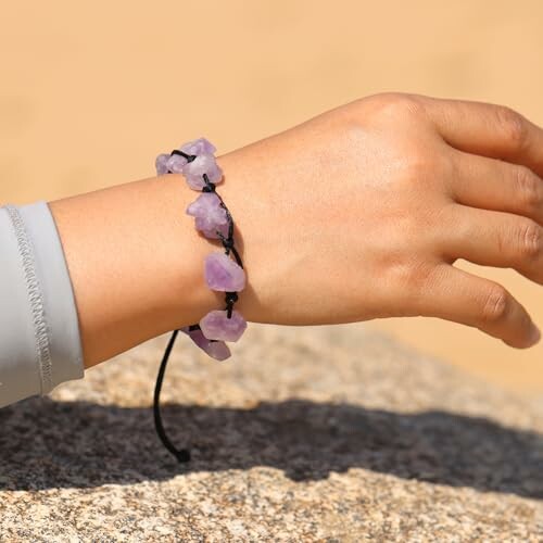 Hand med armband av lila stenar.