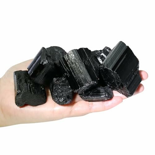 Hand som håller svarta turmalinstenar