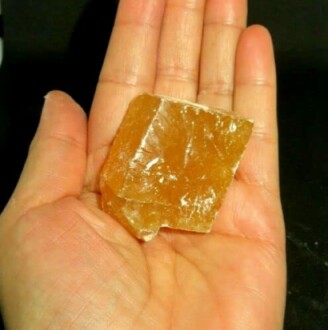 Hand som håller en stor brun sockerkristall.