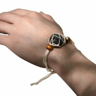 Hand med ett armband av sten och träpärlor