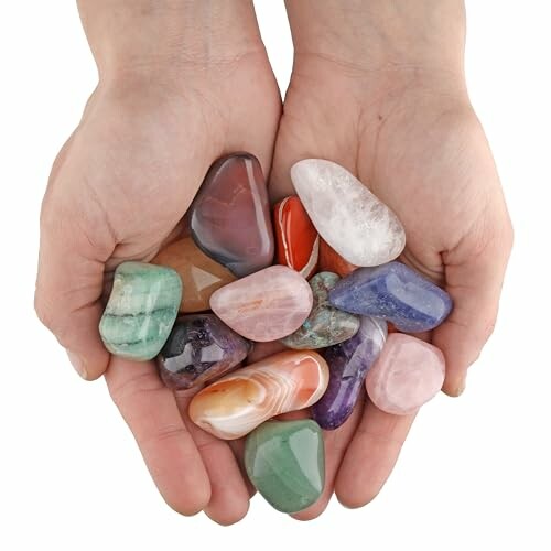 Händer håller glansiga stenar i olika färger.