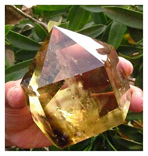 Stor gul kristall hålls i handen.