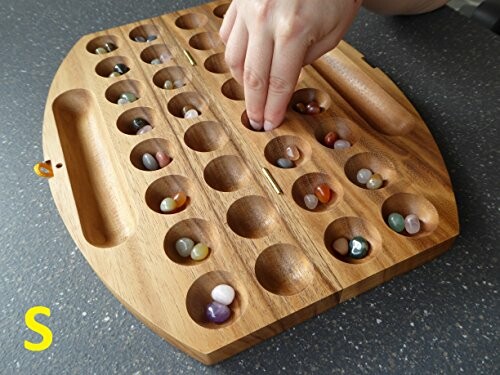 Hand som spelar på ett mancala-spelbräde.