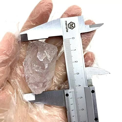 En hand håller en rå kristall och en skjutmått.