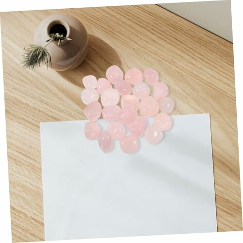 Rosa stenar på ett papper bredvid en vas.