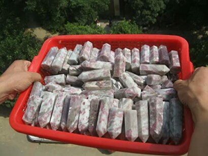 En korg med lila kristallstavar hålls av två händer.