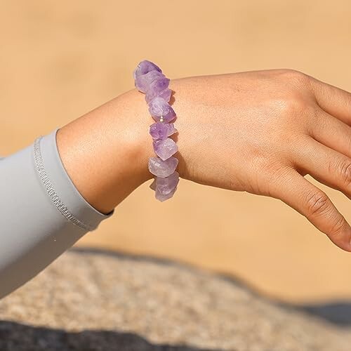Hand med lila ädelstensarmband