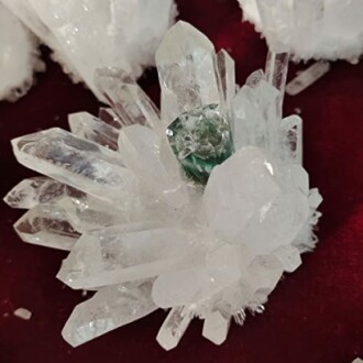 Klar kvarts och grön mineral på röd bakgrund.