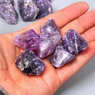Rå ametiststenar i en hand.