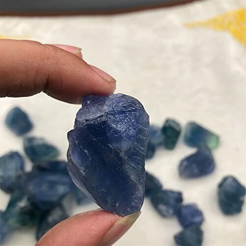 Hand håller en rå blå safirsten