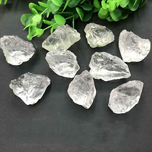 Råa klara kvartsstenar på svart yta.