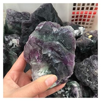 Hand som håller en rå fluoritkristall.