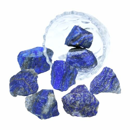 Råa lapis lazuli-stenar faller ur en glasbehållare.