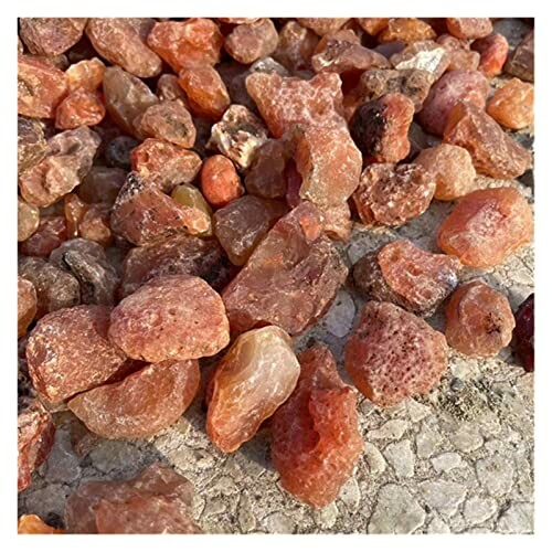 Rå orange karneolstenar på marken.