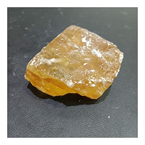 Rå bit av orange selenitsten på svart bakgrund.