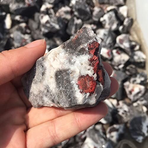 Hand håller rå rodonitsten