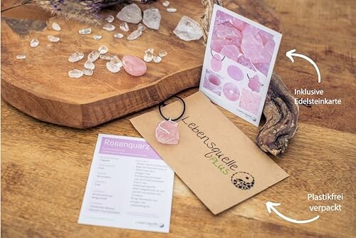 Rosenkvarts nyckelring med informationskort på träbräda.