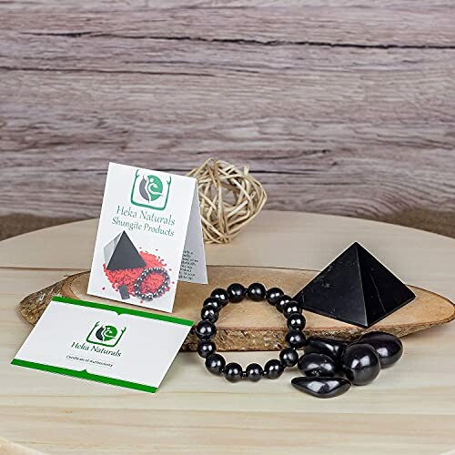 Shungitprodukter inklusive pyramid och armband på träbord.