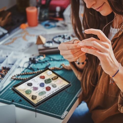 Kvinna skapar smycken vid ett skrivbord med pärlor och verktyg.