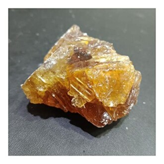 En gulbrun kristall på en mörk yta.